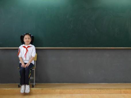 Elementary Student Sitting by Blackboard