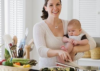 Mujer cocinando bebe en brazos