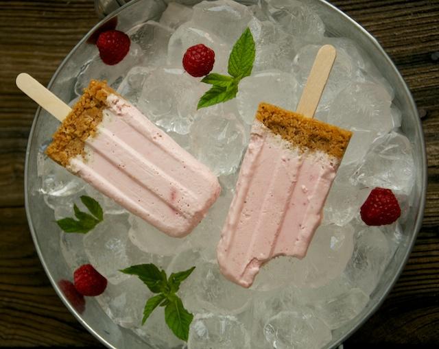 Polos, helados, paletas o popsicles de tarta de queso con fresas y frambuesa.