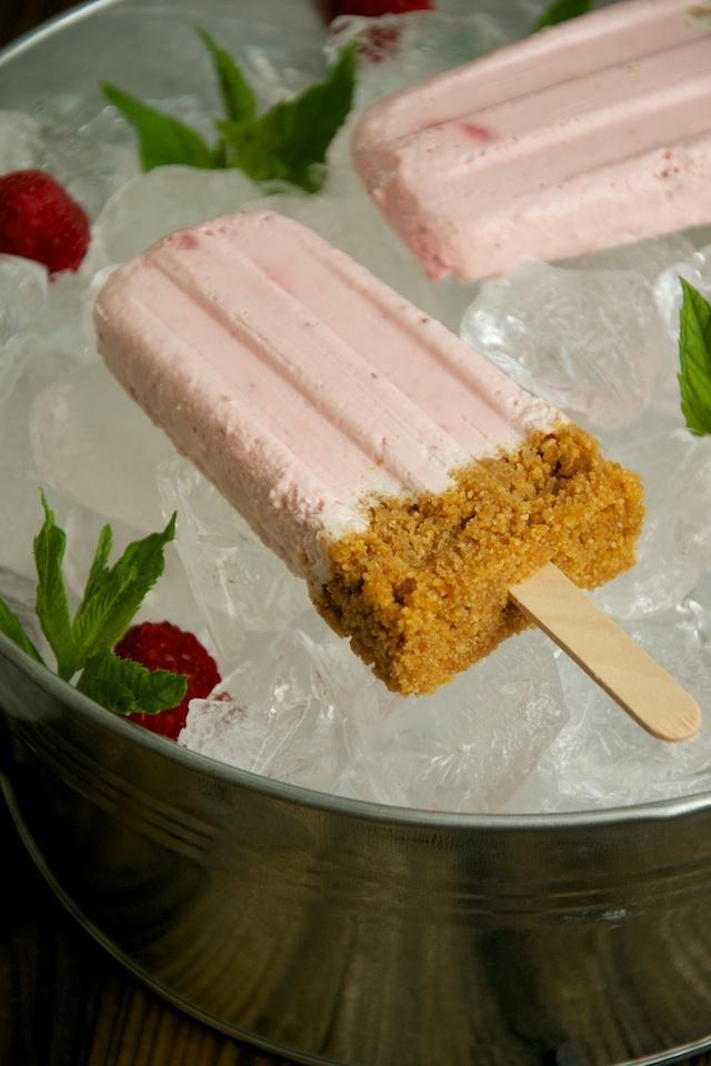 Polos, helados, paletas o popsicles de tarta de queso con fresas y frambuesa.