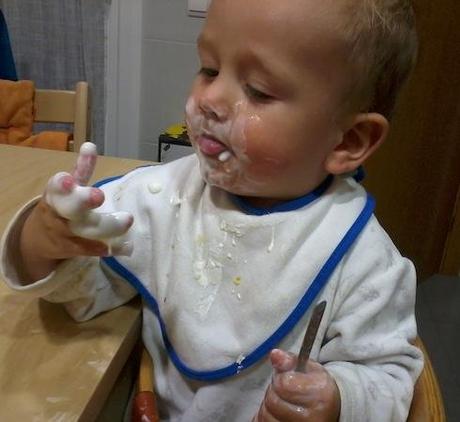 Niño comiendo uogur con las manos