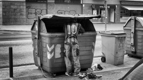 Un hombre busca comida en un contenedor de basura; es España