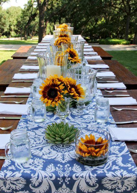 Outdoor summer table with blue and white runner and sunflowers.