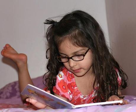niña leyendo un libro en la cama