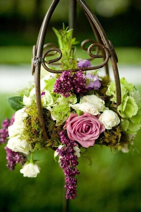 Playing with Nature.  A bronzy lantern frame holds floral in shades of purple, pink and green.  Utilized with a lantern hanger, this would make a beautiful centerpiece.
