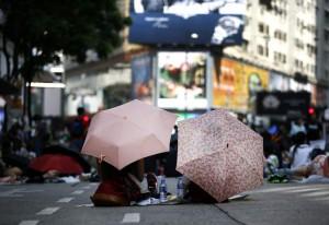 Una revolución que no suena a chino Dos manifestantes protestan sentados y protegidos por sus paraguas en el distrito Central de Hong Kong / DENNIS M. SABANGAN - EFE