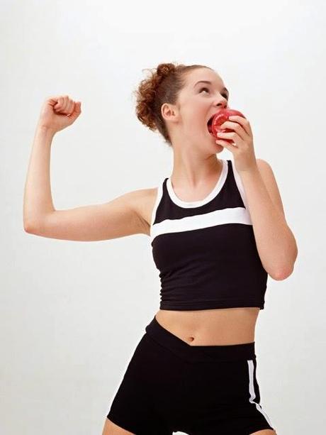 chica comiendo una manzana y mostrando músculo