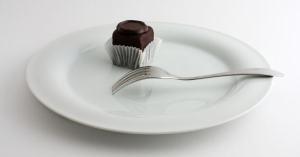 small chocolate cake on a big whit plate on white background