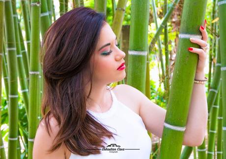 Chica morena posando entre bambu con pelo suelto y paquillaje de fiesta