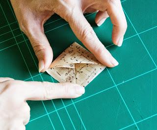 Paso 6.- Guarda las puntas dentro del bolsillo que se habrá formado en una de las mitades del cuadrado Paso 6.- Guarda las puntas dentro del bolsillo que se habrá formado en una de las mitades del cuadrado