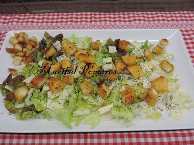 Ensalada con escarola, hoja de roble, lechuga, rabas de calamar, queso, pan tostado en cuadraditos y semillas de amapola.