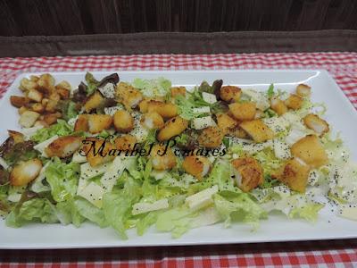 Ensalada con escarola, hoja de roble, lechuga, rabas de calamar, queso, pan tostado en cuadraditos y semillas de amapola.