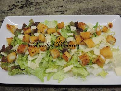 Ensalada con escarola, hoja de roble, lechuga, rabas de calamar, queso, pan tostado en cuadraditos y semillas de amapola.