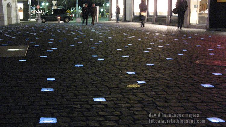 Calle de Ginebra de noche con baldosas iluminadas con saludos en diversos idiomas