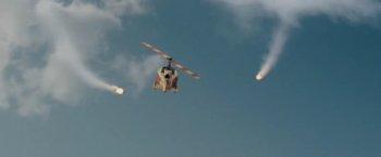 Fotograma de la película que muestra un helicóptero en el aire con el rotor parado, y las estelas de unos misiles convergiendo hacie él
