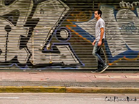 Un hombre pasa frente as un portón grafiteado