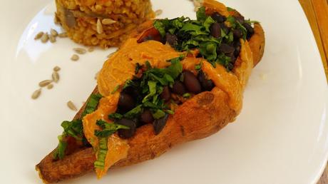 Batatas asadas rellenas de judías negras, arroz y quinoa con salsa de cacahuete y salsa de tahini