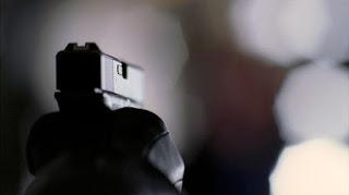 Reseña #239. El asesino hipocondríaco, de Juan Jacinto Muñoz Rengel Pistola empuñada por un asesino que no se ve, apuntando a un fondo distorsionado.