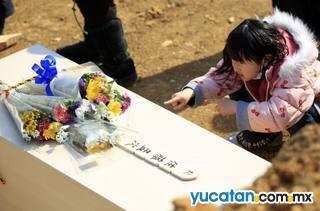 Una niña se despide de un familiar, víctima del terremoto y del tsunami en Yamamoto, prefectura de Miyagi. Miles de cadáveres han sido enterrados en depósitos provisionalmente por el gobierno, aunque la tradición era incinerarlos Una niña se despide de un familiar, víctima del terremoto y del tsunami en Yamamoto, prefectura de Miyagi. Miles de cadáveres han sido enterrados en depósitos provisionalmente por el gobierno, aunque la tradición era incinerarlos