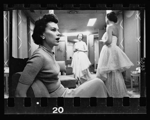 23. Woman seated in chair while another woman models a dress