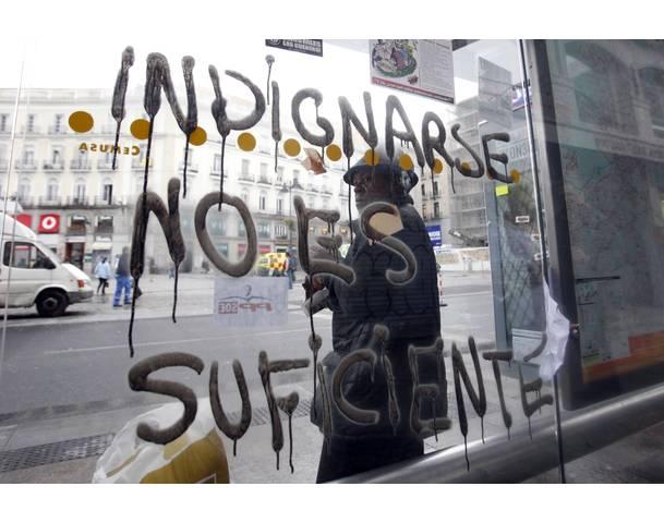 DEMOCRACIA REAL, YA! A man waits for a bus as he stands at a bus stop at Madrid's famous landmark Puerta del Sol
