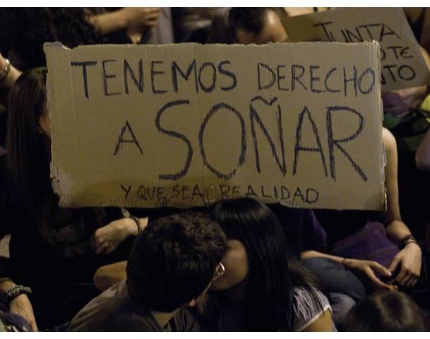 DEMOCRACIA REAL, YA! Demonstrators kiss underneath a banner in Madrid's Puerta del Sol during sixth day of protests