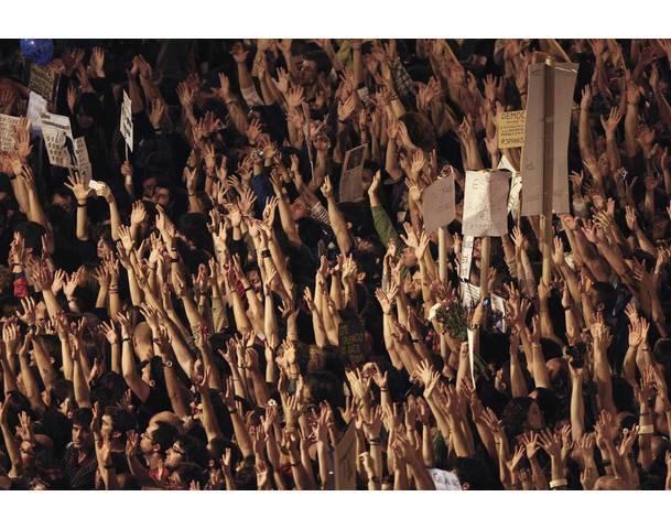 DEMOCRACIA REAL, YA! Demonstrators raise their arms just after midnight as they fill up Madrid's Puerta del Sol during sixth day of protests