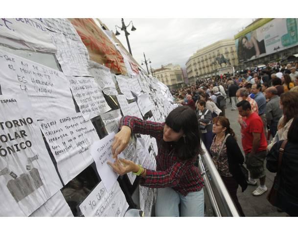 DEMOCRACIA REAL, YA! A demonstrator pastes slogans on a wall in Madrid's famous landmark Puerta del Sol