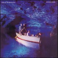 An album cover showing four men in a rowing boat inside a blue lit sea cave. Two men are stood side-by-side at the back of the boat each holding an oar, the third man is sat in the centre of the boat and the fourth is leaning over the front of the boat with his hand in the water. The band's name is in the top-left of the cover and the album's name is in the top-right, both in white text.