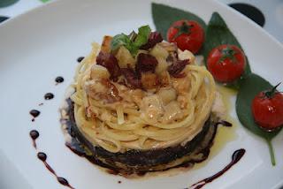 Linguine sobre cama de cebolla caramelizada al Oporto, coronados con una crema de manzana y confit de pato, finalizados con una reducción de Oporto