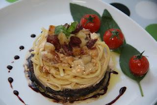 Linguine sobre cama de cebolla caramelizada al Oporto, coronados con una crema de manzana y confit de pato, finalizados con una reducción de Oporto