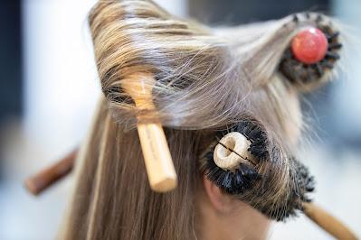 Cabeza femenina con melena larga y varios cepillos grandes enrollados en el pelo