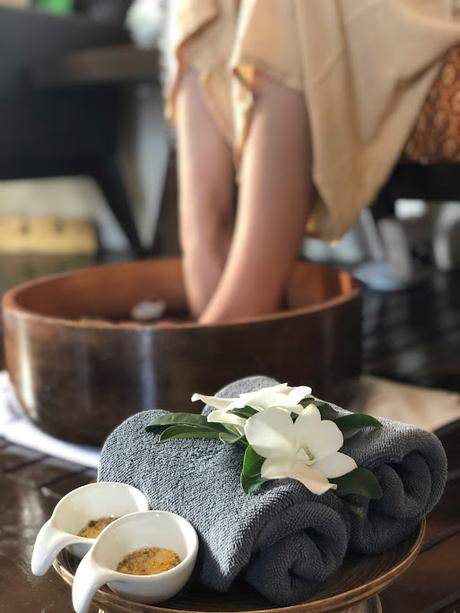 Mujer con los pies dentro de un barreño con agua y una bandeja con toallas delante Mujer con los pies dentro de un barreño con agua y una bandeja con toallas delante