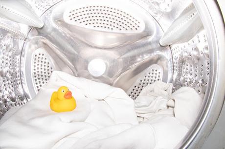 Tambor lleno con ropa blanca y un patito de goma