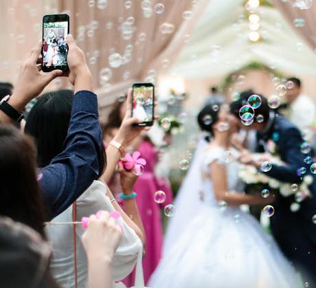 Invitados fotografiando a los novios mientras se besan al finalizar la ceremonia Invitados fotografiando a los novios mientras se besan al finalizar la ceremonia