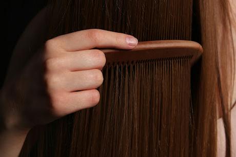 Cómo Aplicar Correctamente un Aceite para Sellar las Puntas Mujer pasando un peine sobre el pelo