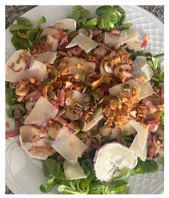 Ensalada templada con cama de canĂłnigos, queso de cabra, bacon crujiente, champiĂąones y lascas de queso padano fundido