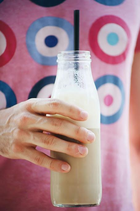 Persona sosteniendo una botella de horchata ocn una pajita