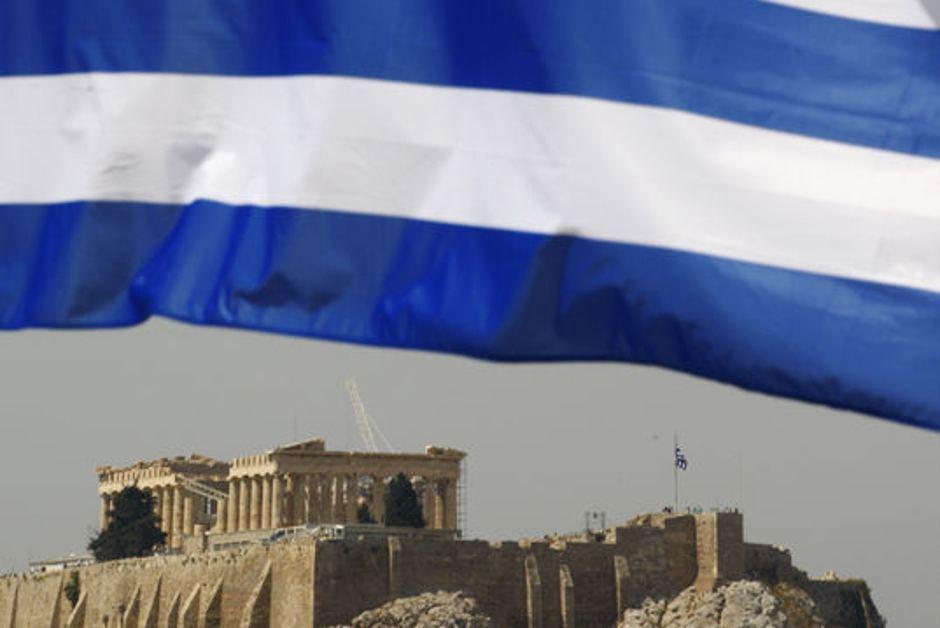 A Greek flag waves in front of the temple of the Parthenon in Athens