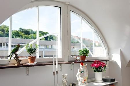 ventana redondeada suelo de parquet sofá gris sillas eames muebles blancos decoración limpieza en ático diáfano estilo nórdico estilo escandinavo electrodomésticos silenciosos decorar pisos decorar con muebles de ikea decoración estilo nórdico decoración escandinava decoración diáfana decoración de áticos cocina blanca blog deco blog de interiorismo blog de decoración ático diáfano 