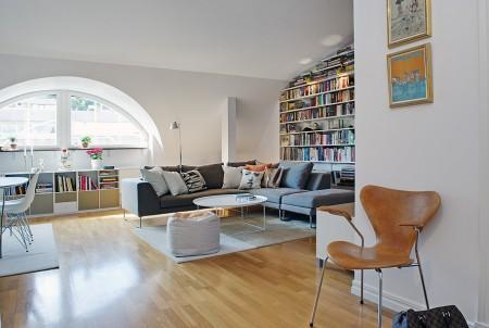 ventana redondeada suelo de parquet sofá gris sillas eames muebles blancos decoración limpieza en ático diáfano estilo nórdico estilo escandinavo electrodomésticos silenciosos decorar pisos decorar con muebles de ikea decoración estilo nórdico decoración escandinava decoración diáfana decoración de áticos cocina blanca blog deco blog de interiorismo blog de decoración ático diáfano 