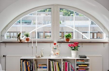 ventana redondeada suelo de parquet sofá gris sillas eames muebles blancos decoración limpieza en ático diáfano estilo nórdico estilo escandinavo electrodomésticos silenciosos decorar pisos decorar con muebles de ikea decoración estilo nórdico decoración escandinava decoración diáfana decoración de áticos cocina blanca blog deco blog de interiorismo blog de decoración ático diáfano 