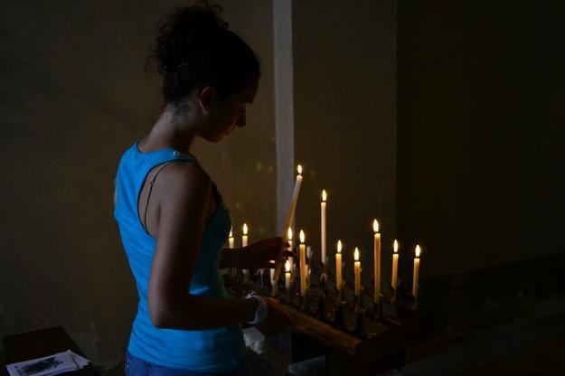 Jani encendiendo una vela en una pequeña capillita de Volterra
