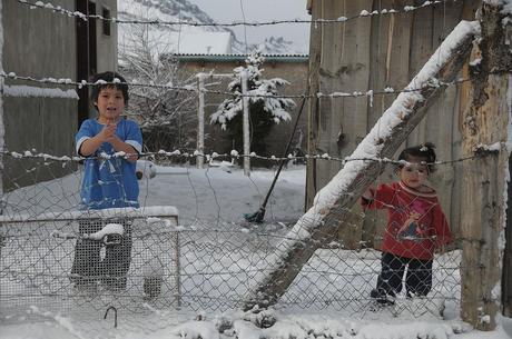 Dos niños desabrigados en la nieve en una vivienda precaria