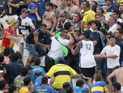 Aficionados del Boca Junior agreden a un guardia de seguridad, durante el partido cotnra el River Plate, el domingo en Buenos Aires. 