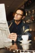 Man reading newspaper at cafe