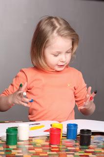 Niña pintando con pintura de manos.