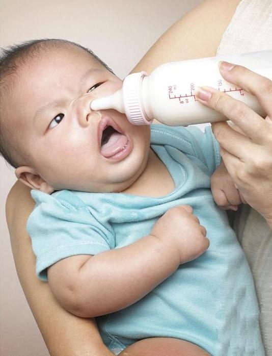 niño tomando el biberon con madre despistada