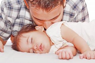 papá besando a su bebé dormido