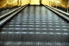 Bajo unas escaleras mecánicas. Al final de la cinta ...